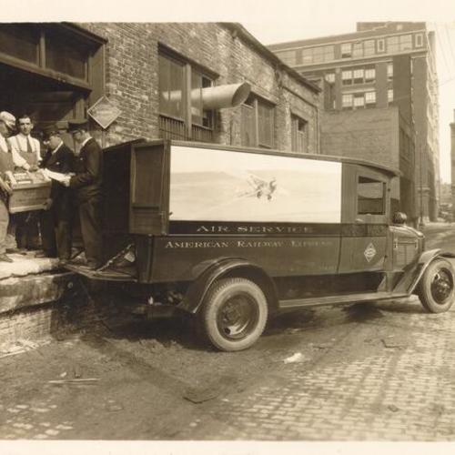 [Four men loading an American Railway Express truck]
