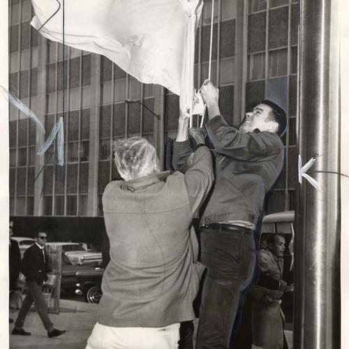 [North Vietnam flag is being hauled down by federal guards in front of the new Federal building]