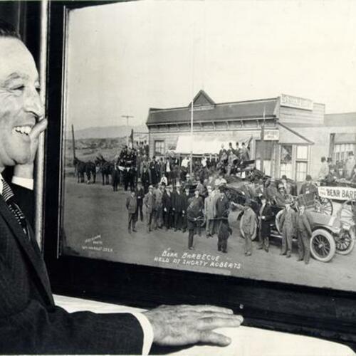 [Shorty Roberts posing with a picture of the Sea Breeze Resort, now known as Roberts at the Beach]