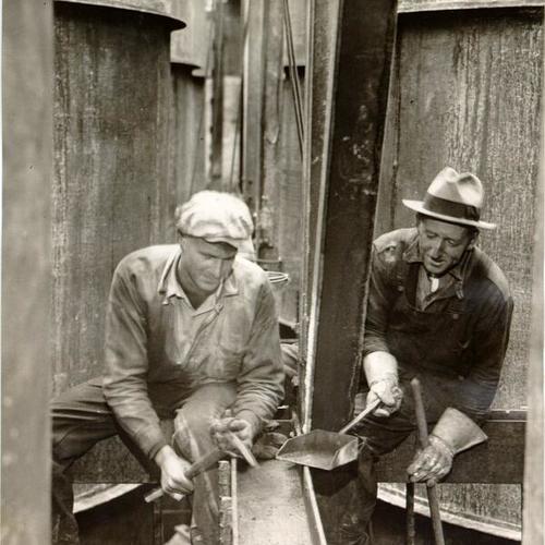 [Two bridge workers inside a caisson used during the construction on the San Francisco-Oakland Bay Bridge]