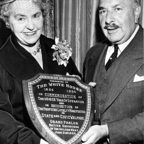 [Mrs. Joseph Noonan presenting White House department store president Michel Weill with a plaque in recognition of the store's contributions to state and civic welfare]