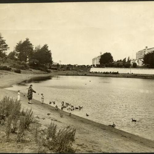 [Woman and two children feeding ducks at Mountain Lake]