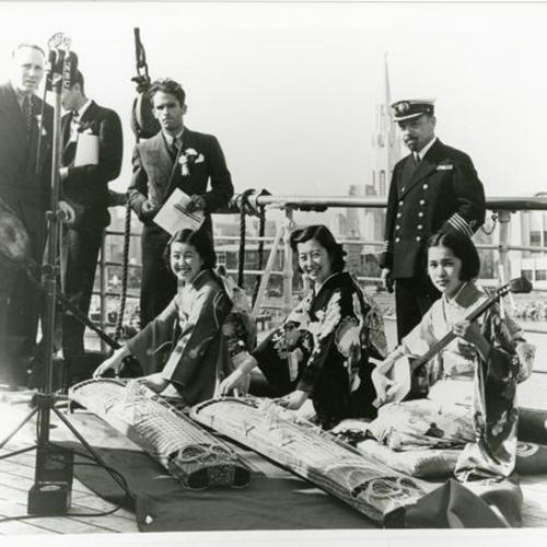 [On the deck of ship named Tatsuta Maru is the captain of the ship, NBC news reporters and Sumi playing the Shamisen for the celebration at the fair on Treasure Island]