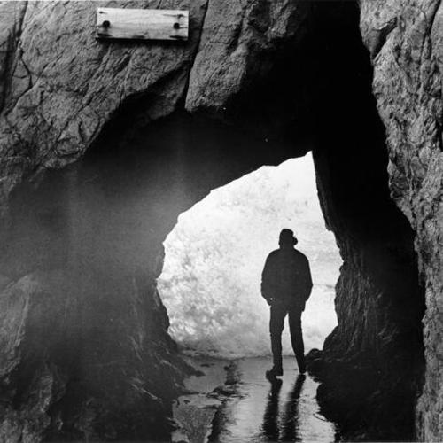 [Man standing in a cave near Sutro Baths]