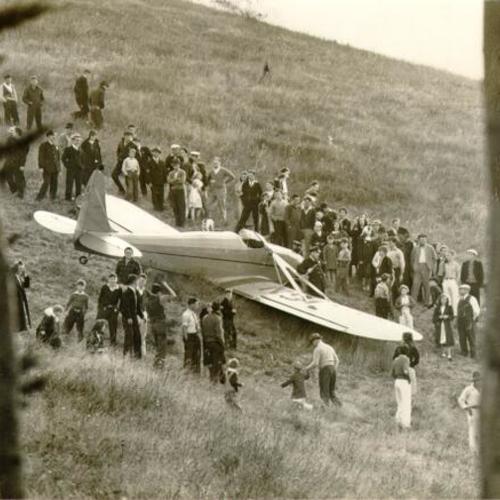 [Crowd of people standing around a wrecked plane on Twin Peaks]
