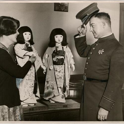 [Dorothy Schnable showing Japanese dolls "Miss Yokohama Tokio" to Officer Dave Dolileman]