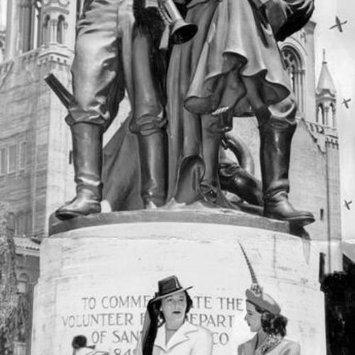 [Mrs. Russell Blackman, Mrs. Arnold Scheier and Miss Betty McCann standing in front of a bronze statue in Washington Square Park commemorating the Volunteer Fire Department of 1849 - 1866]