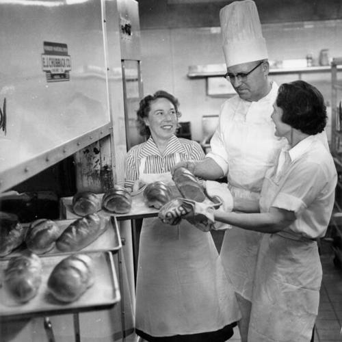 [George Miller inspecting loaves of bread as they come out of the oven in the kitchen at Galileo High School]