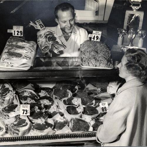 [Butcher Mickey Petrini selling meat to Margaret Carleton at the meat counter in Petrini Plaza on Fulton Street at Masonic Avenue]