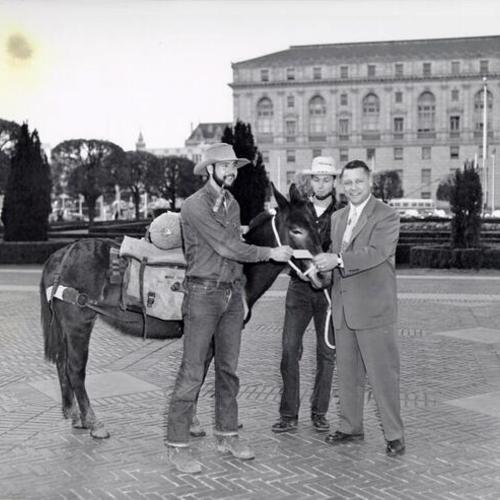 [Jack Wilms, Dick Bastear and J. McAteer standing in Civic Center Plaza with a horse]