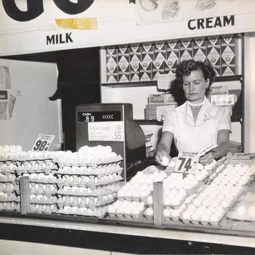 [Employee working behind a counter in the dairy department at the Crystal Palace Market]