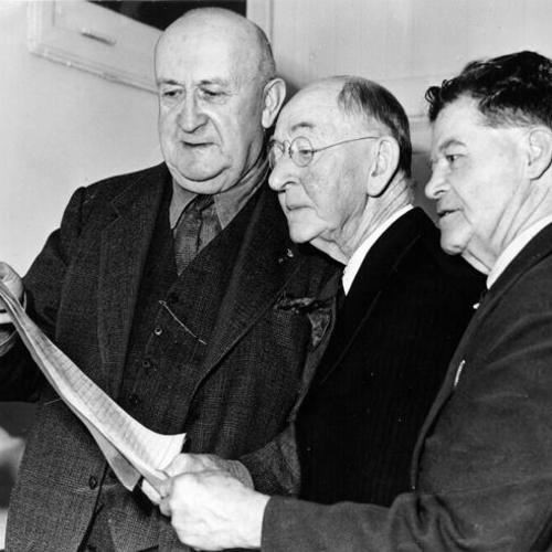 [John T. Johnson, Hugh Thomas and Warren Shoefelt looking at a list of signatures on a petition to preserve San Francisco's cable cars]