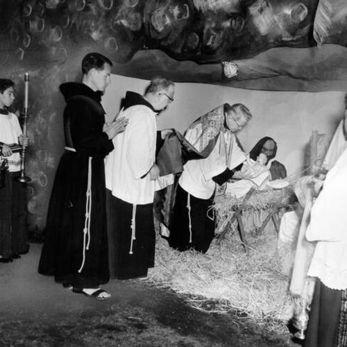 [Father Alfred Boeddeker (center), with Brother Phillip (left) and Father Terence Cronin (right) at reproduction of the Nativity Scene in St. Boniface Schoolyard]