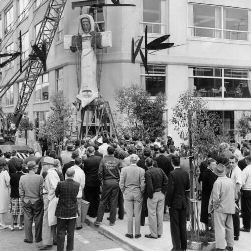[Crowd watching statue of Saint Francis of Assisi being put in place in front of Bermuda Building in Oakland]