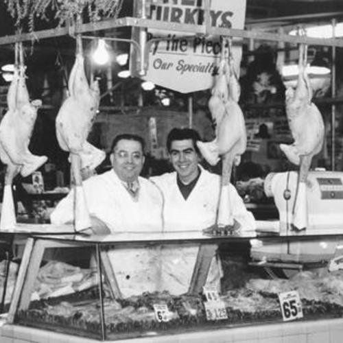 [Tommy Zanca and his assistant standing ready to help customers at one of four poultry shops in the Crystal Palace Market]