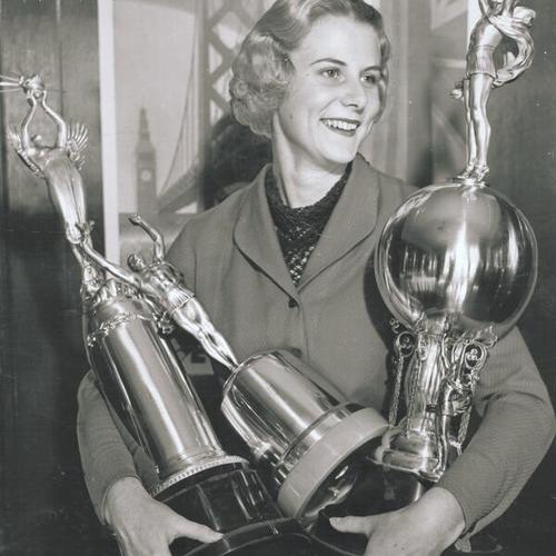 [Miss Doris Schuler displaying trophies for winning float, band and drill in the opening day celebration parade for San Francisco-Oakland Bay Bridge]
