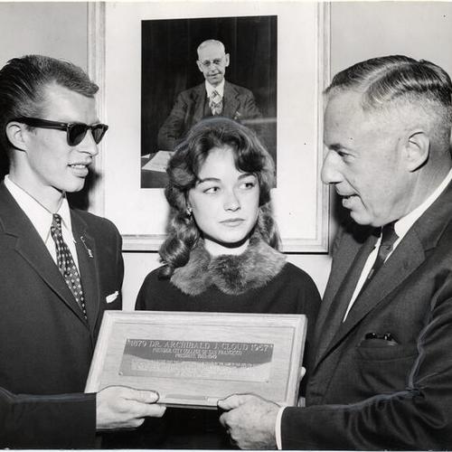 [Dick Cottrell and Tessa Thomsen presenting a plaque to City College of San Francisco president Louis Conlan honoring school founder A. J. Cloud]