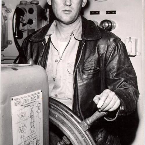 [John Riddell standing at the wheel of the refrigerator ship Fleetwood]