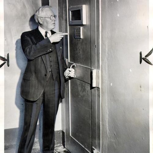 [Warden James A. Johnston of Alcatraz Prison pointing to a door which kept rioting prisoners from escaping]