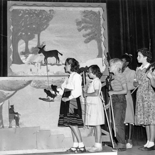 [Evangeline Powell and other children looking over equipment for a play at Everett Junior High School]