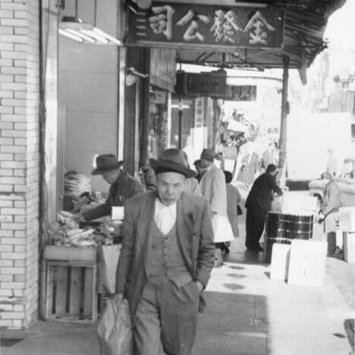 [Elderly man walking on a sidewalk in Chinatown]