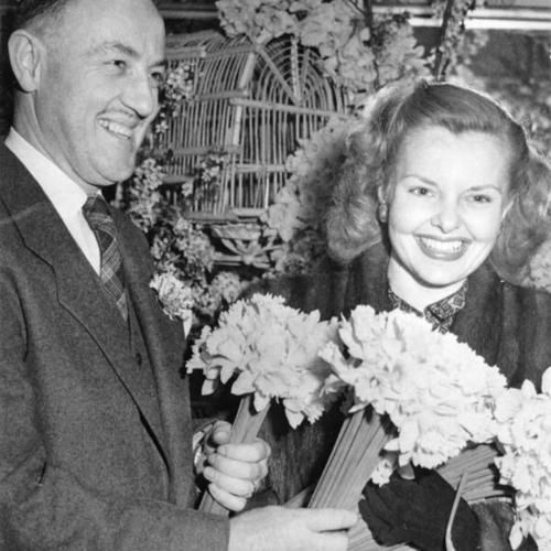[Acting mayor Chester R. MacPhee and actress Elizabeth Fraser posing with bouquets of daffodils]