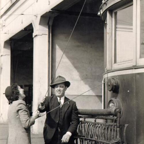 [William R. Ratto showing San Francisco News reporter Lois Thomas how to manipulate a streetcar trolley cable]
