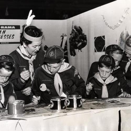 [Stevie Levin, Mrs. Larry Kenney, Kelley Randle, Billy Bacigalupi, Ricky Levin and Mrs. Derek Levin painting Indian headdresses at the 1957 Scout-O-Rama at the Cow Palace]