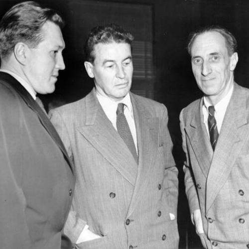 ["Harry Renton Bridges (right) doesn't seem to be as disturbed about his five-year prison sentence as his two defense attorneys, James McInnis (left) and Vincent Hallinan (center)"]