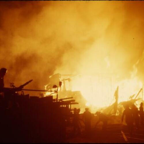 [Fire crews battle a collapsed burning building]