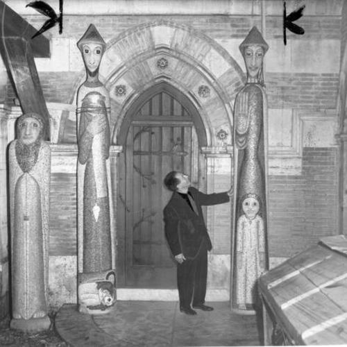 [Bennie Bufano, sculptor, standing next two three-dimensional mosaics he created for the Church of St. Francis of Assisi]