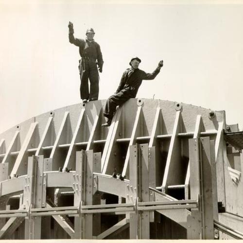 [Two construction workers atop the south tower of the Golden Gate Bridge]