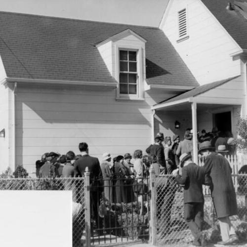 [Crowd of people waiting in a line to enter a home located near the Civic Center]
