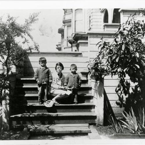 [Two brothers sitting, on steps of a home on Octavia Street, with their mother]