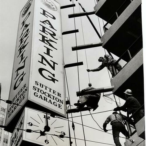 [Workmen hoisting the four-sided sign at the Sutter-Stockton Shoppers Garage]