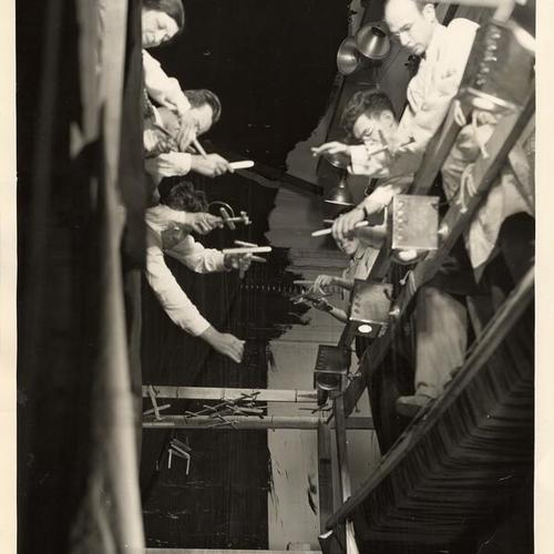 [Men and woman working backstage with marionettes]