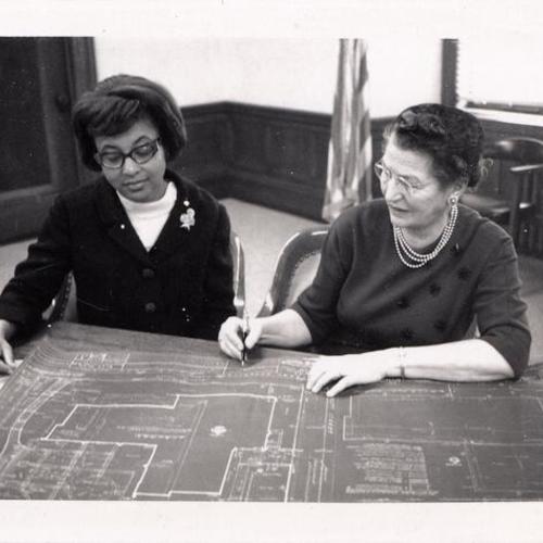 [Two women looking at architectural drawing of the Western Addition Branch Library]