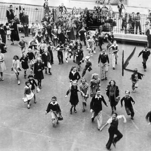 [Children running through the school yard gate of Redding School on the first day of class]