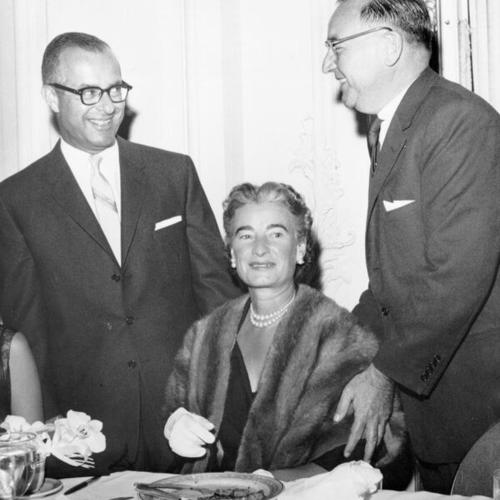 [Attorney General Edmund G. (Pat) Brown (right) and Judge Stanley Mosk (left), assist Mrs. Brown with her chair at testimonial in Mosk's honor]