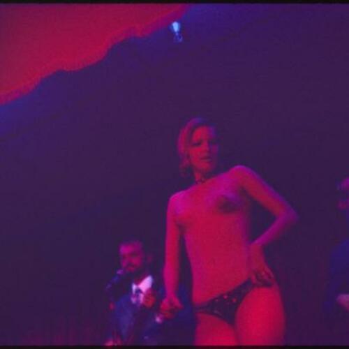 Striptease artist performing on stage with band in background