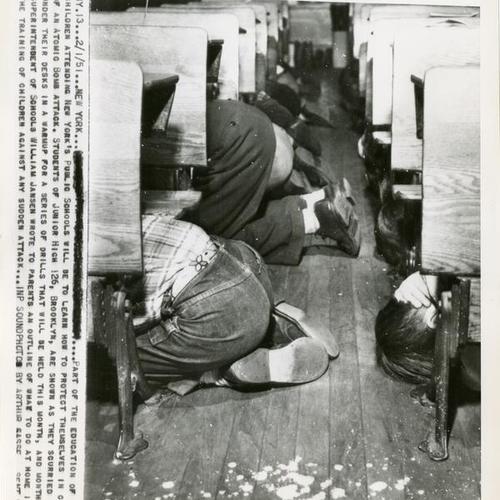 [Junior high school students in Brooklyn, New York practice hiding under their desks for an atomic attack drill]