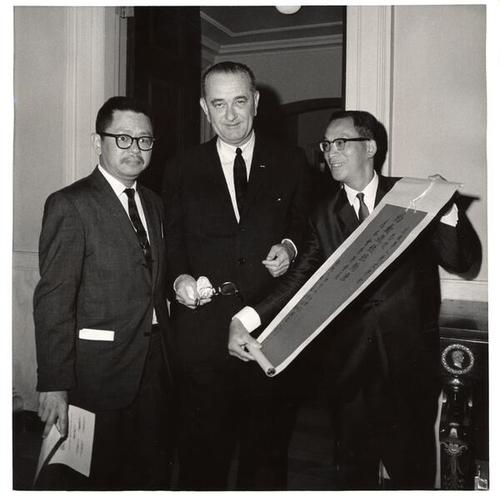 [C.H. Kwock Secretary of the Chinese Historical Society and H.K. Wong the Society's vice-President present the membership scroll to President Johnson in the White House]