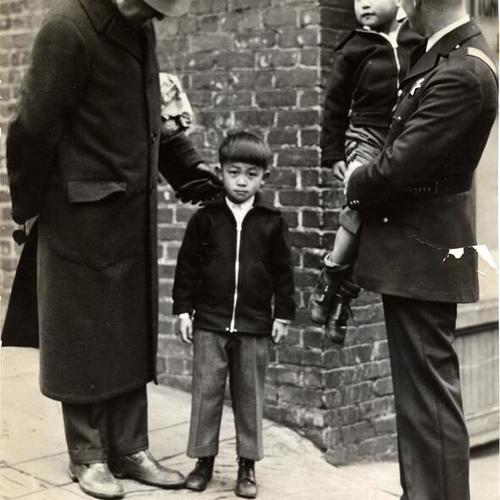 [Inspector John Manion (left) talking with one of the Ong twins while policeman, Henry Kiernan (right), is holding in his arms the other Ong twin boy]