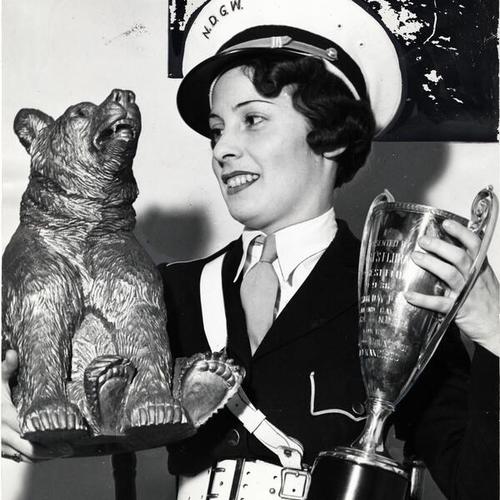 [Gladys McQueen holding trophy and golden bear]