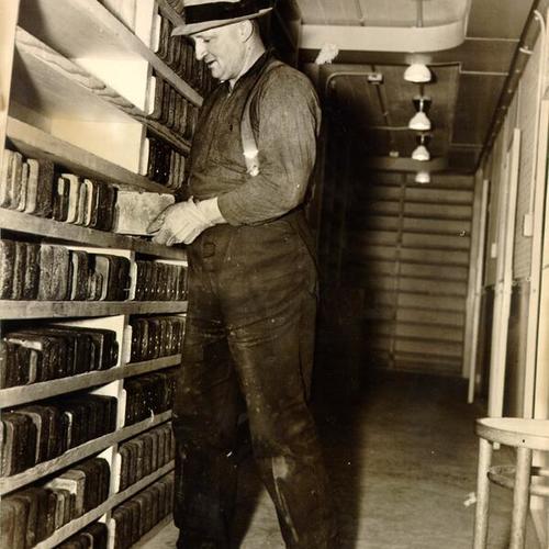 [Unidentified employee shelving gold bars at the U. S. Mint]
