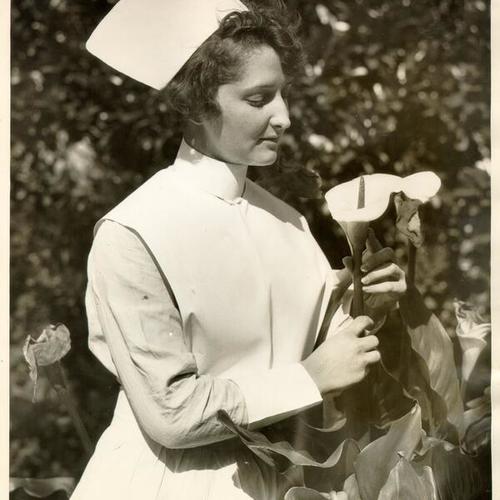 [Inez Marie Keller posing with a flower in a garden at St. Luke's Hospital]
