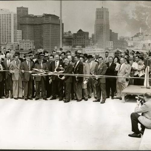 [Public officials (center) Frank B. Durkee, state director of public works; Roy N. Buell, president of the Down Town Association, and Supervisor Henry Rolph in the ribbon cutting ceremony to open the first section of the Embarcadero Freeway]