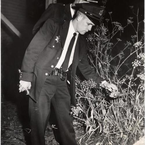 [Policeman Jerome Cassidy picks up gun used in shooting]