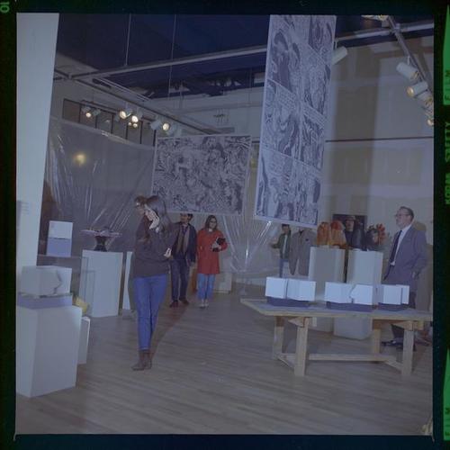 View of gallery interior with patrons looking at art