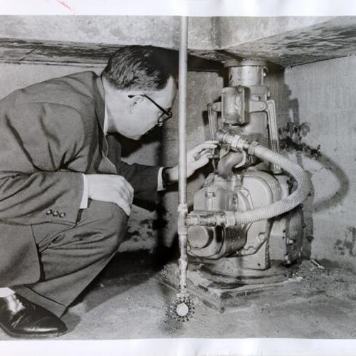 [Ralph A. Ratcliff, Duff-Norton district sales manager at San Francisco, inspecting equipment installed by his company at Bank of America's San Francisco International Airport branch]